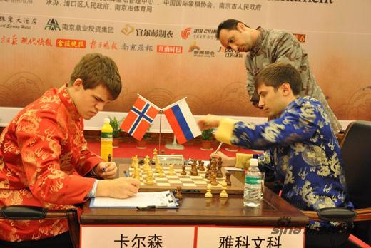 Magnus Carlsen contre Dimitri Jakovenko sous loeil de Veselin Topalov. Mais bon sang pense le Bulgare, jaurai dû y penser ! Ecrire une lettre de protestation. (PS. En fait, il note le coup joué).