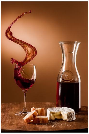 Du vin rouge dans un verre et un pichet, du pain et du camembert fixés sur une table à roulettes, qui est lancée contre un butoir, provoquant le débordement du verre. Du vin rouge dans un verre et un pichet, du pain et du camembert fixés sur une table à roulettes, qui est lancée contre un butoir, provoquant le débordement du verre.