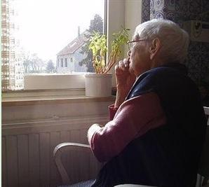 vieille dame regardant sa fenêtre, article sur le thème de l'assurance dependance dans les contrats mtuelles santé
