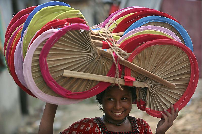 Lundi 19 avril, cette jeune fille transporte des éventails, faits main, pour les vendre sur un marché près de Dhaka, au Bangladesh. 