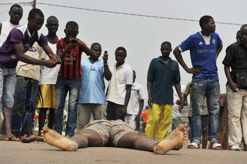Des habitants d’Abobo, quartier populaire d’Abidjan, en Côte d’Ivoire, observent le corps d’un homme qui a été retrouvé mort, tué par balle, à la suite de heurts qui ont éclaté, mercredi 12 janvier, entre les partisans d’Alassane Ouattara et les forces loyales au président sortant, Laurent Gbagbo.
