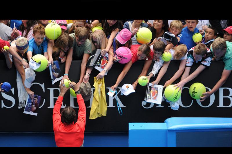 Illusion, montage et rigolade... Rafael Nadal signe des autographes après sa victoire expéditive lors du premier tour de l’Open d’Australie, mardi 18 janvier, à Melbourne. Le numéro un mondial a bénéficié de la blessure au genou du brésilien Marcos Daniel pour s’imposer en 47 minutes, en moins de deux sets 6-0, 5-0.