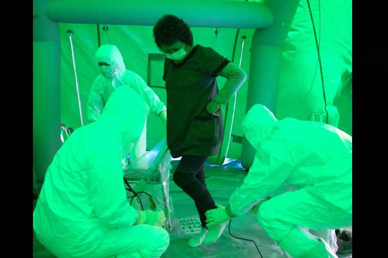 Dans des tentes spécialisées, une unité médicale équipée de combinaisons protectrices contrôle la radioactivité de la population d’Hitachi, mercredi 16 mars. 