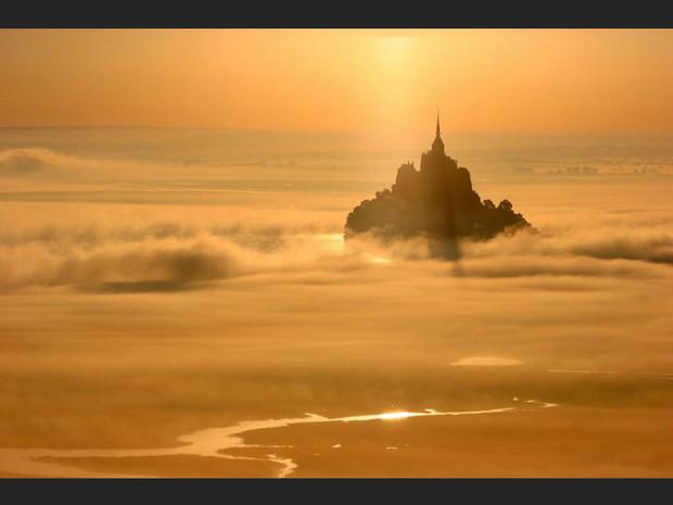 Le Mont-Saint-Michel se détache dans la brume orangée, en Normandie (France). Le Mont-Saint-Michel se détache dans la brume orangée, en Normandie (France).