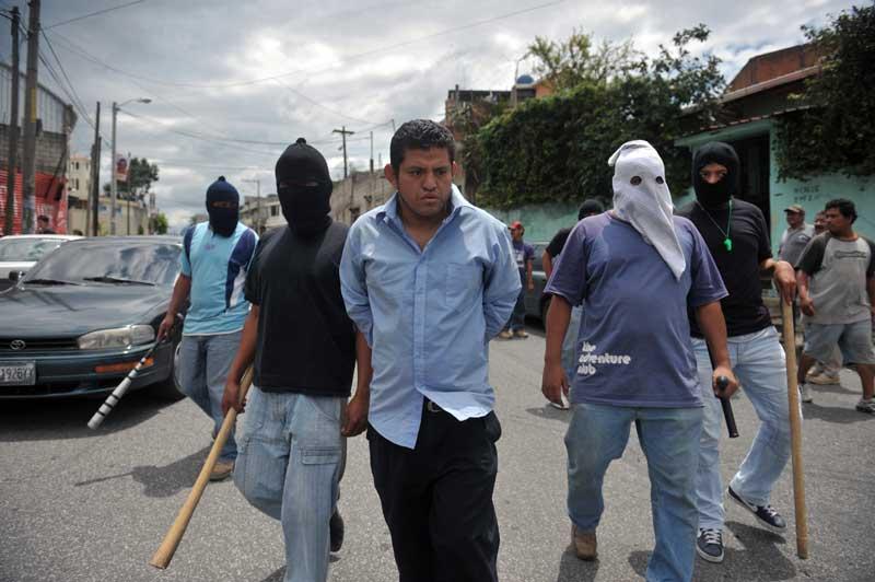<b></div>Justice expéditive</b>. Sous les cagoules qui masquent leurs visages, des habitants de la banlieue de Guatemala City qui ont décidé de faire justice eux-mêmes après avoir été victimes de la violence des gangs. Cet homme soupçonné de faire partie de la Mara Salvatrucha, l'un des pires groupes criminels d'Amérique du Sud, vient d'en faire les frais. La Mara Salvatrucha revendique plusieurs dizaines de milliers de membres aux États-Unis, au Canada, au Mexique et en Amérique Centrale. 