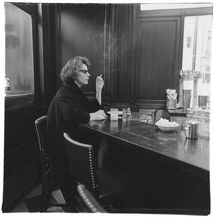 Woman at a counter smoking, N