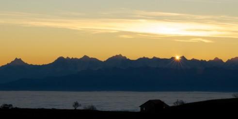 Photo d'un joli lever de soleil sur les alpes depuis le sommet du Creux-du-Van. Lever de soleil sur les alpes