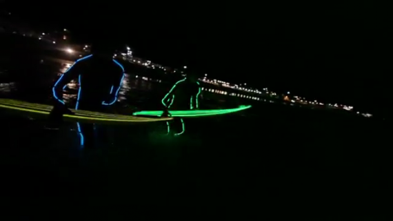 Surf nocturne avec combi et board à néons sur Bondi beach !