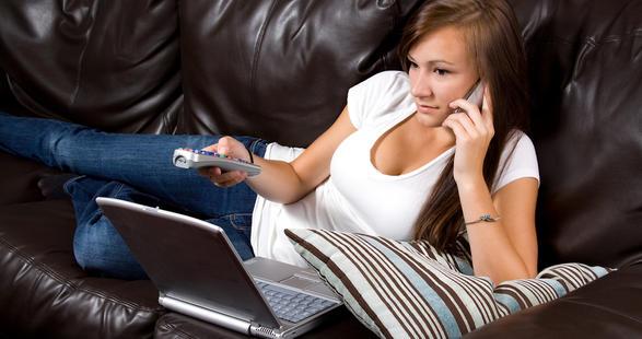 jeune fille devant la télévision avec un ordinateur et un mobile