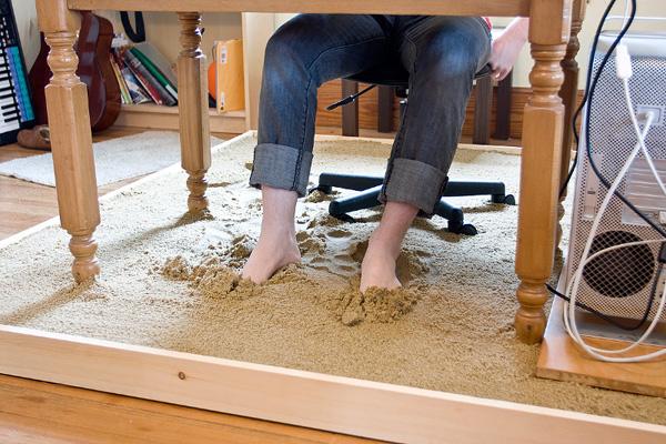 Un graphiste travaille les pieds dans le sable au bureau