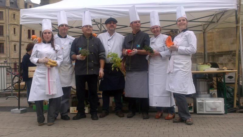 DSC_0056 Les chefs et cuisiniers en habits de travail posent avec des fruits et légumes devant le stand du Crepaq.
