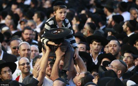Accablé: Un petit garçon a l'air accablé comme il est reporté sur la foule observant le corps d'un chef religieux charnière être effectuée par