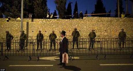 Les agents de la police des frontières israéliennes sécuriser le périmètre cimetière.  Comme les fondus de commotion, un disciple se tient soigneusement reflétant