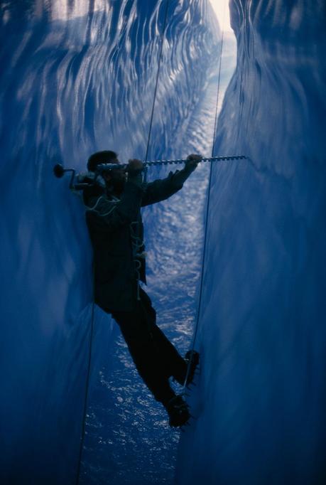 Wedged in a crevasse, Tylor Kittredge drills holes for marker pegs in an Alaskan glacier, February 1967.Photograph by Christopher Knight, National Geographic