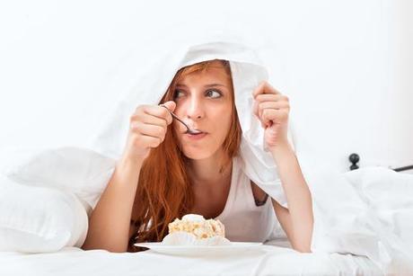 jeune femme rousse qui mange sous les couvertures