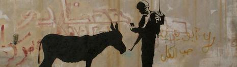 Banksy - Un tag sur le mur de Gaza pour l'opération Santa's Ghetto. On voit un soldat devant un âne