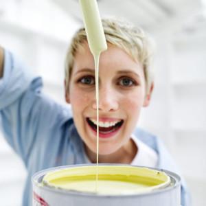 Young Woman Holding a Paint Brush Dipped in a Paint Bucket