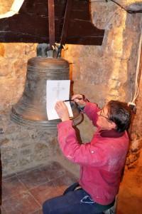 Serge Porre calque les inscriptions de la cloche à l'intérieur de l'église