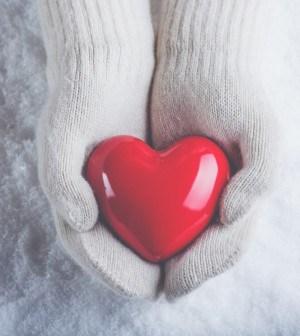 CROYEZ EN VOTRE BONNE ETOILE ! Female hands in white knitted mittens with a glossy red heart on a snow winter background. Love and St. Valentine cozy concept.