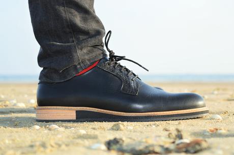 Profil Chaussures derby SUBTLE en cuir noire avec un jean noir délavé et des chaussettes rouge