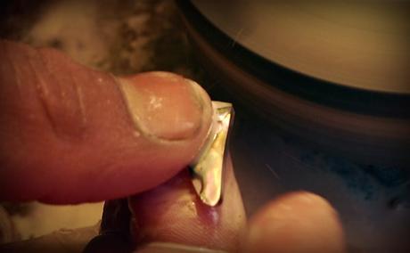polissage d'une pierre naturelle de nacre  d'abalone pour faire un bijou en argent