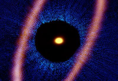 A composite image of the Fomalhaut star system - ALMA data (orange) shows the distinct ring, the central dot is the star and the optical data (blue) comes from the Hubble Space Telescope. The dark region is the coronographic mask filtering the star's light