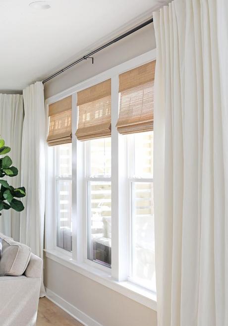 Conseils et astuces pour mettre en valeur ses fenêtres store matière naturelle marron claire rideaux blancs plante verte salon épuré lumineux