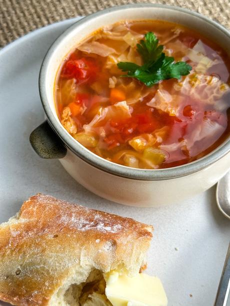 soupe au chou dans un bol rustique avec un morceau de pain baguette et du beurre