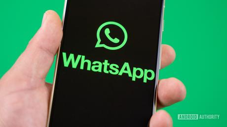 Tenir un smartphone avec le logo WhatsApp sur l'écran photo stock