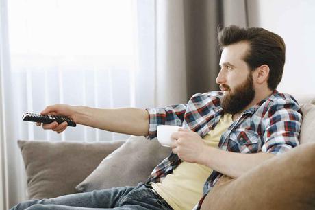 Meuble TV suspendu : comment le choisir et l’installer ? Homme qui regarde la télévision