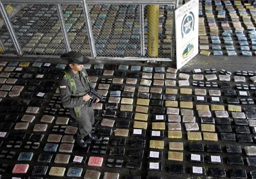 Un agent de police des promenades sur les paquets de cocaïne à Buenaventura, Colombie, principal port maritime sur la côte du Pacifique, du lundi 23 Mars 2009. La Police colombienne a saisi 3,5 tonnes de cocaïne dans un récipient contenant de la graisse végétale à destination de Mexico