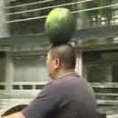 En scooter, une pastèque en équillibre sur sa tête