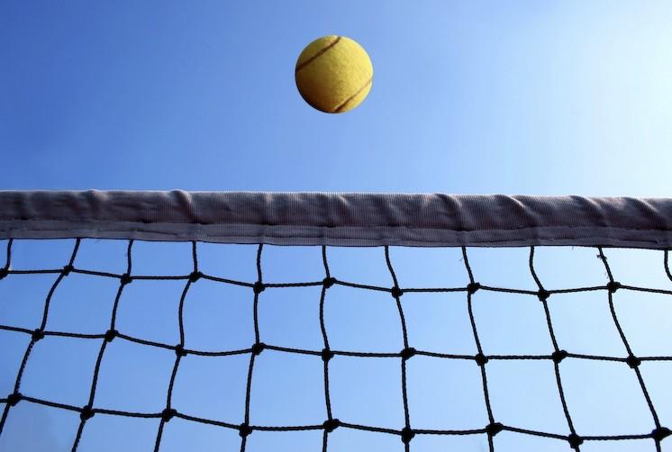 filet de tennis et une balle devant un ciel bleu