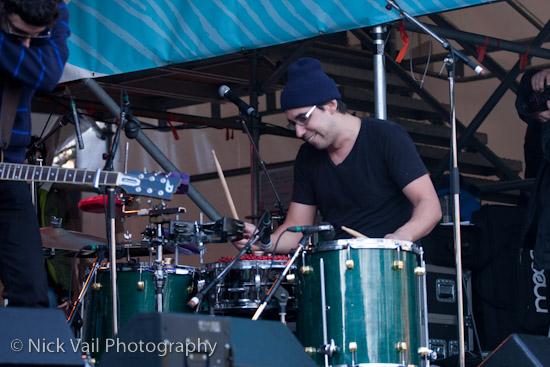 Julien Sagot of Karkwa beating on the drums with a smile - Karkwa  Live on Stage Whistler 2010