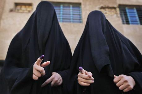 Élections en Irak. Deux femmes voilées montrent leurs doigts trempés d’encre à la sortie d’un bureau de vote de Bagdad.