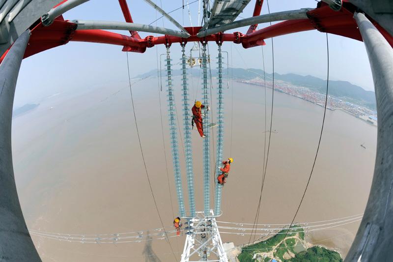 Mardi 25 mai, ces ingénieurs vérifient la bonne installation d’isolateurs sur des pylônes électriques de la ville de Hangzhou, dans la province de Zhejiang, au sud de Shanghai. 