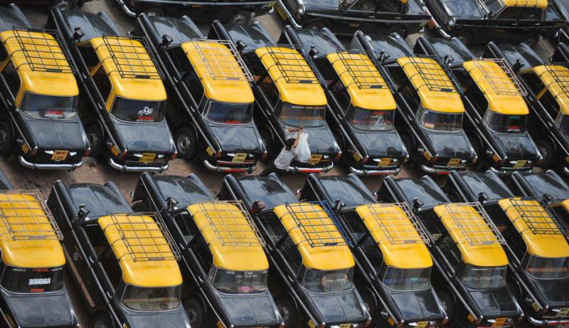 Mardi 22 juin, un homme marche au milieu de voitures garées à Mumbai, en Inde. Au total, ce sont plus de 85.000 taxis et près de 100.000 auto rickshaws qui sont restés immobilisés suite à une grève des chauffeurs qui réclament une hausse du tarif au kilomètre. 