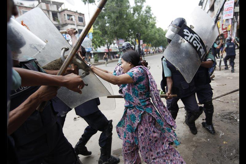 Mercredi 30 juin, lors d’une manifestation à Dhaka, au Bangladesh, cette ouvrière du textile, tente d’échapper aux coups que lui portent ces policiers. Les protestataires réclament une hausse des salaires. 
