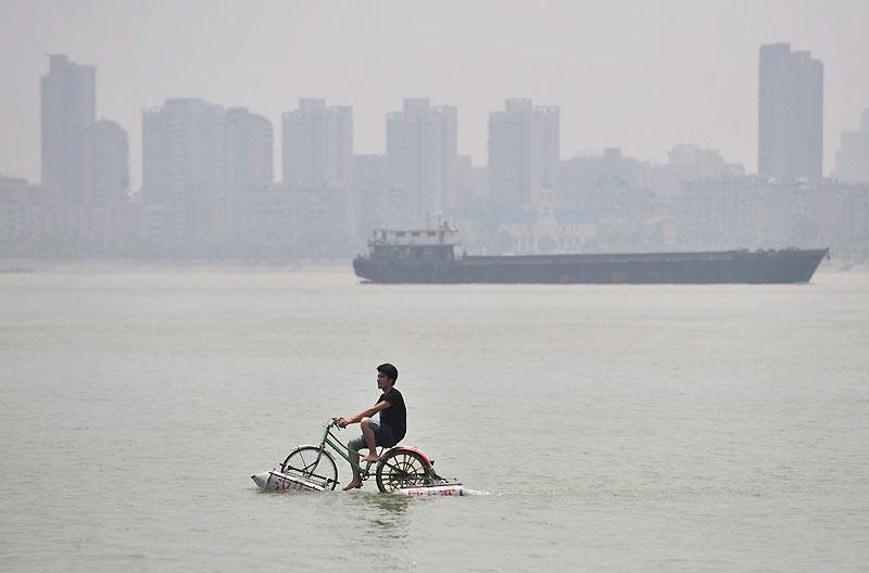 Cet homme se déplace avec un vélo flottant sur le fleuve qui traverse Wuhan, dans la province de Hubei, en Chine, mercredi 16 juin. 