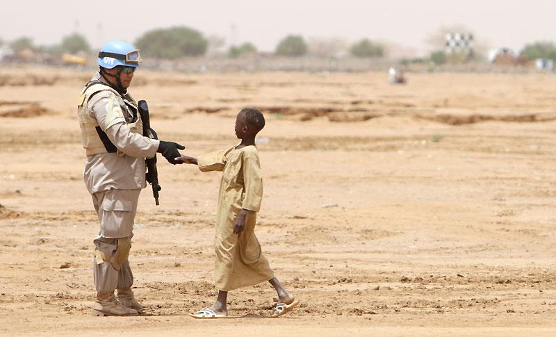 Un soldat de l'ONU serre la main à un jeune garçon à El-Fasher, capitale de la province du Darfour Nord, au Soudan, lundi 5 juillet. Le même jour, au même endroit, les participants à une conférence internationale sur la paix ont appelé les mouvements armés du pays à négocier avec le gouvernement.