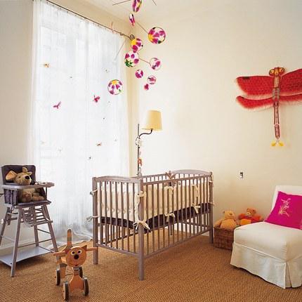 Une chambre lumineuse pour bébé, avec un lit à barreaux et une chaise haute couleur parme, des accessoires colorés aux murs