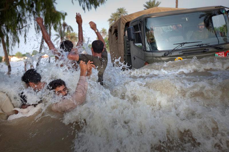 Mercredi 11 août, dans le district de Muzaffargarh, dans l’est du Pakistan, des réfugiés qui tentent de fuir les inondations croisent un camion qui amène des provisions alimentaires. 