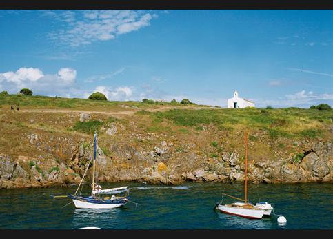 Sous la bienveillante garde de Notre-Dame-de-Bonne-Nouvelle, la plus ancienne chapelle de l'île, le petit port de La Meule, unique refuge de la côte sauvage, accueille dans son ventre de granit des embarcations telles ce vieux petit cotre de pêche ou ce corsaire tirant sur son amarre.