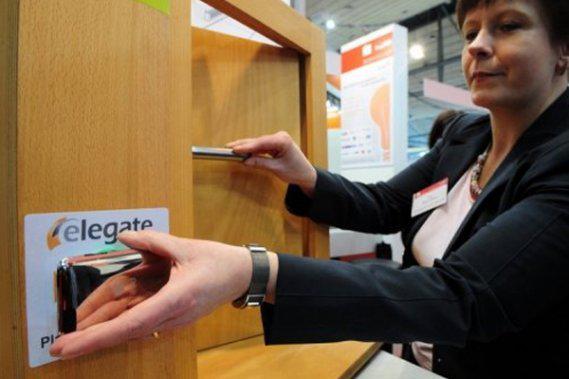 Une femme ouvre une porte avec un téléphone cellulaire au salon Cebit en mars 2010, en Allemagne