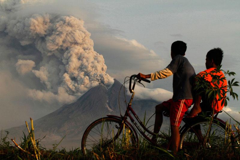 Ces deux enfants à vélo observent l’éruption du volcan Merapi, en Indonésie, mercredi 10 novembre. L'activité volcanique s'est calmée sur le mont, mais de fortes secousses sont toujours ressenties et le niveau d'alerte maximale reste maintenu. 