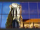 La basilique Notre-Dame de Nice se reflète dans les vitres d’un immeuble moderne, créant un lien fébrile entre deux ères.