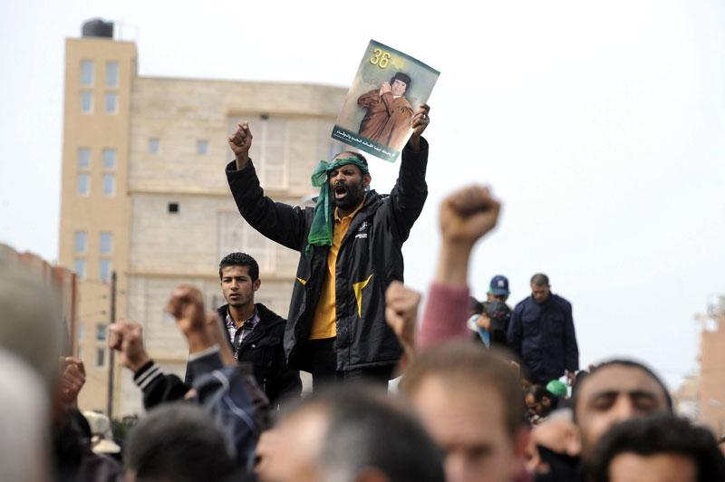 Dans la ville de Sabratha, à 65 km à l’ouest de Tripoli, des militants pro-Kadhafi brandissent des portraits du «Guide», lundi 28 février. Si la majorité du pays s’insurge contre le dictateur libyen, ses quelques partisans continuent de lui rester fidèles.