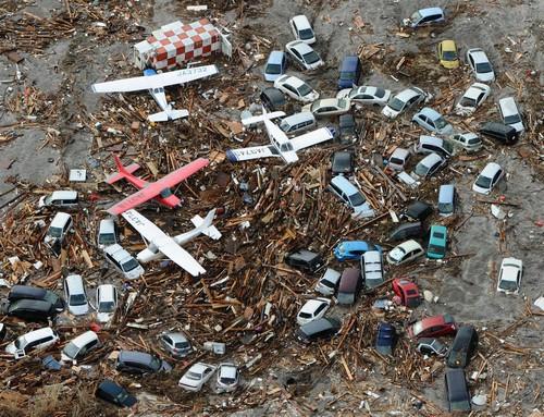 Avions et voitures recouverts de débris à l'aéroport de Sendai