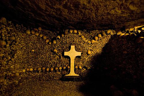 Un ossuaire et une croix dans les catacombes de Paris