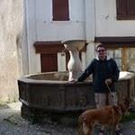Najac : greg et zap devant la fontaine des Consuls (1344) : Cette fontaine publique creusée dans un bloc monumental de granite rose, occupe la partie centrale du village. Une dédicace en latin rappelle la date de sa construction et les noms des consuls qui en furent les commanditaires. Les armes de Najac (un château fort), un évêque bénissant (l'évêque de Rodez Gilbert de Cantobre), un roi portant la barbe, et des personnages aux figures énigmatiques en ornent la cuve décagonale. P1050446.JPG
